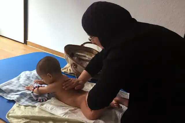 Baby wird sanft auf einer Matte massiert