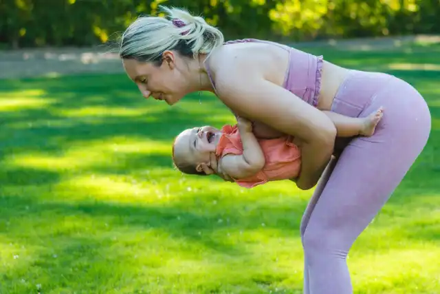 Mutter macht eine Übung zur Rückbildung mit ihrem Baby im Arm
